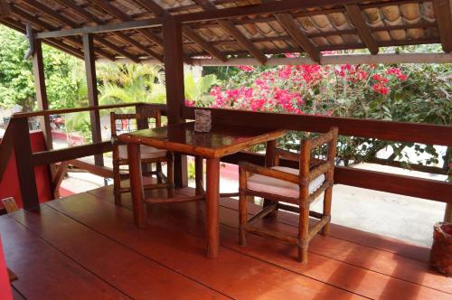 a wooden table and chairs on a porch with flowers at Pousada Recanto do Espelho in Praia do Espelho
