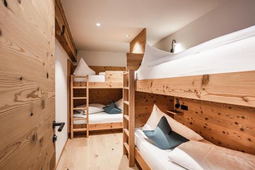 two bunk beds in a room with wooden walls at Hotel Lener in Vipiteno