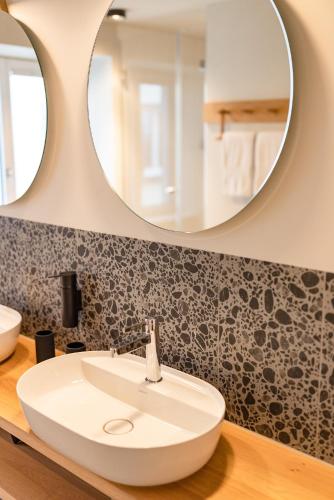 a bathroom with a white sink and a mirror at Gyger Restaurant Confiserie B&B in Thusis