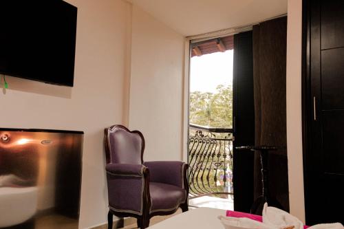 a hotel room with a chair and a balcony at Hotel Plaza Garibaldi in Caldas
