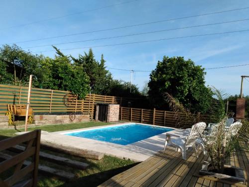 a swimming pool in a garden with two chairs next to it at Casa de Campo, con Pileta y Asador Criollo!! - "La Ranchada" in Gualeguaychú