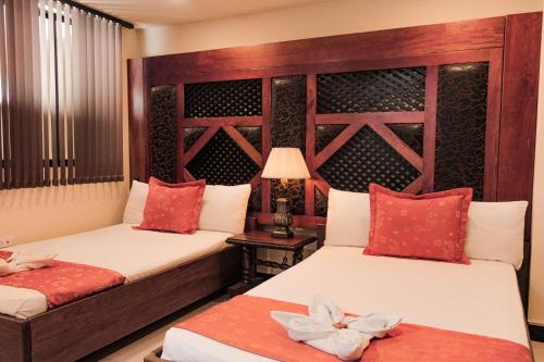 two beds in a room with red and white pillows at Hotel Plaza Garibaldi in Caldas