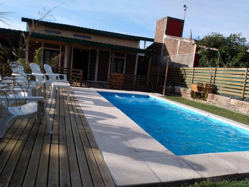 una piscina con sedie bianche accanto a una casa di Casa de Campo, con Pileta y Asador Criollo!! - "La Ranchada" a Gualeguaychú