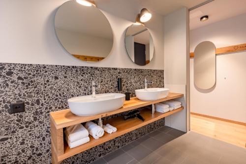 een badkamer met 2 wastafels en 2 spiegels bij Gyger Restaurant Confiserie B&B in Thusis