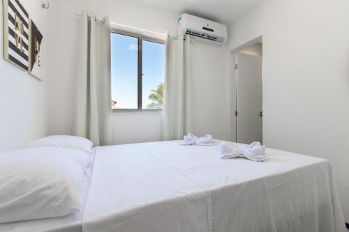 ein weißes Schlafzimmer mit einem weißen Bett und einem Fenster in der Unterkunft Beach Townhouses #C5 - Aconchego por Carpediem in Aquiraz