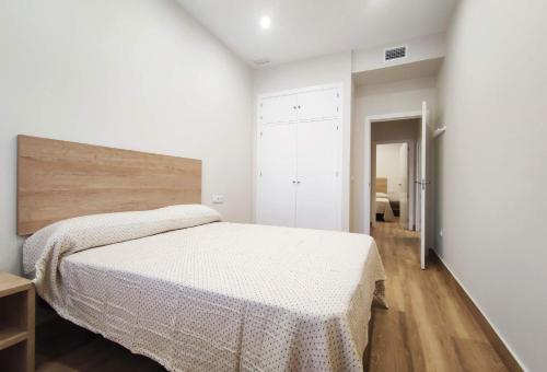 a white bedroom with a bed and a wooden floor at APARTAMENTOS SANLUCAR CASA A in Sanlúcar de Barrameda