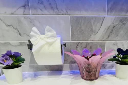 a vase with a white bow on a counter with flowers at 3 Bedroom 2 Bathroom Bungalow by CozyNest in Earley