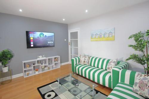 a living room with two green striped couches and a tv at 3 Bedroom 2 Bathroom Bungalow by CozyNest in Earley
