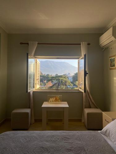 a bedroom with a bed and a window with a table at Central Park Rooms in Tirana