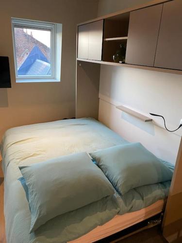 a bed with two pillows in a room with a window at Cambrai:studio style loft in Cambrai