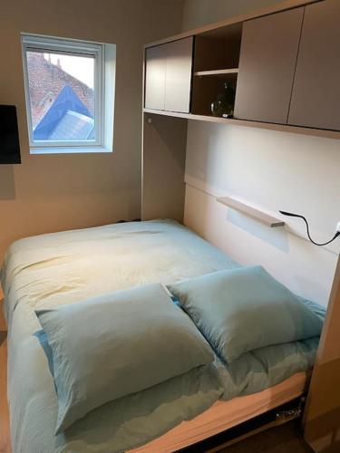 łóżko z 2 poduszkami w pokoju z oknem w obiekcie Cambrai:studio style loft w mieście Cambrai