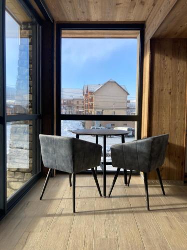 uma mesa e cadeiras num quarto com uma grande janela em Appart Hôtel Le JAS em Ancelle