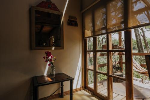 a vase of flowers on a table next to a window at Cabañas en el Bosque a 5 minutos del mar - Estancia CH in Punta del Este