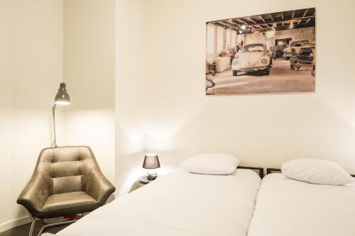 2 camas en una habitación con silla y una foto de un coche viejo en Getaway Studios Leuven, en Lovaina