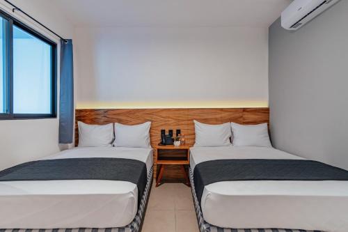 two twin beds in a room with a window at Hotel Mody Merida in Mérida