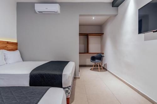a hotel room with a bed and a tv at Hotel Mody Merida in Mérida