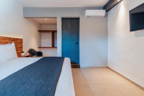 a bedroom with a bed and a blue door at Hotel Mody Merida in Mérida