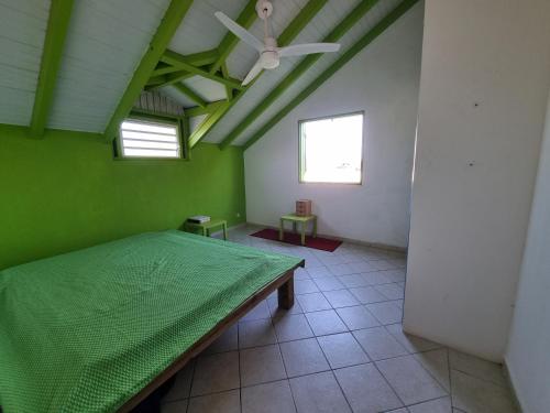 um quarto verde com uma mesa e uma ventoinha de tecto em Villa Caraïbes em Sainte-Rose