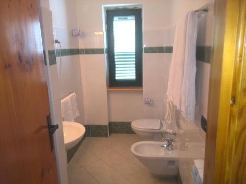 La salle de bains est pourvue de 2 toilettes, d'un lavabo et d'une fenêtre. dans l'établissement Hotel La Fattoria, à Camigliatello Silano