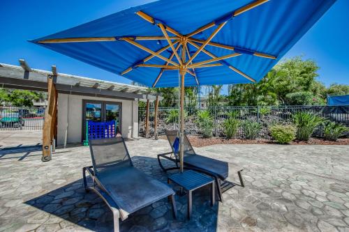 two chairs and a blue umbrella on a patio at Greens At Waikoloa J101 in Waikoloa Village