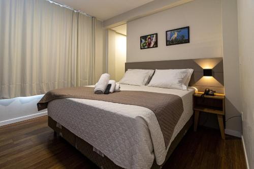 Gaivotas Praia Hotel في فلوريانوبوليس: غرفة نوم مع سرير مع منضدة ونافذة