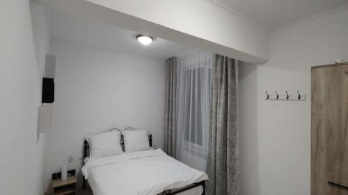 Habitación blanca con cama y ventana en Camera de la Bunici - o poarta catre oriunde, 