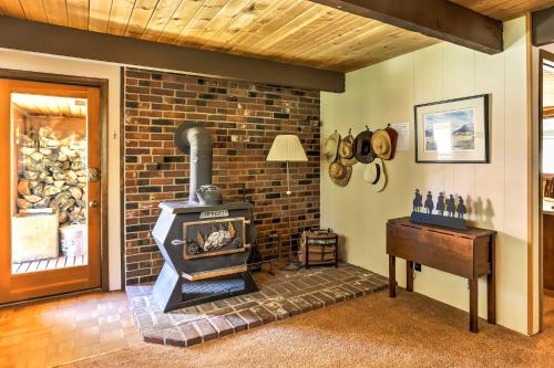 a brick fireplace in a living room with a wood stove at Riverside Winthrop Chalet with Hot Tub and 2 Decks! in Winthrop