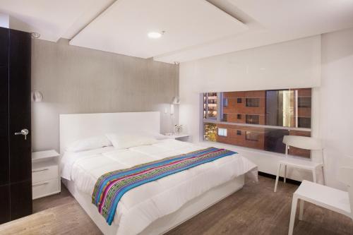 Un dormitorio con una gran cama blanca y una ventana en PapaGayo City, en Quito