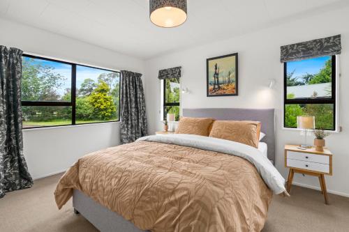 um quarto com uma cama e duas janelas em Regent Retreat - Martinborough Holiday Home em Martinborough