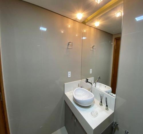 a white bathroom with a sink and a mirror at Excelente localização na Barra -Climatizado-Garagem in Salvador