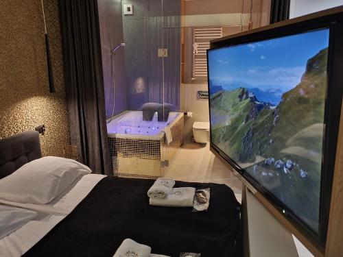 a hotel room with a large tv and a bed and a tub at Jacuzzi Glass-House Central Station in Krakow