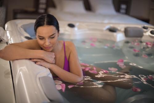 a woman is sitting in a bath tub at Spa Pleasure Apartman in Novi Sad