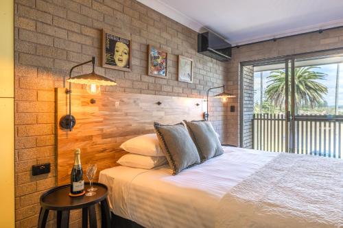 a bedroom with a bed and a brick wall at Bermagui Beach Hotel in Bermagui