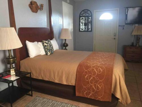 ein Schlafzimmer mit einem Bett, zwei Lampen und einem TV in der Unterkunft A Smaller Piece of Heaven, Near by Lackland AFB in San Antonio