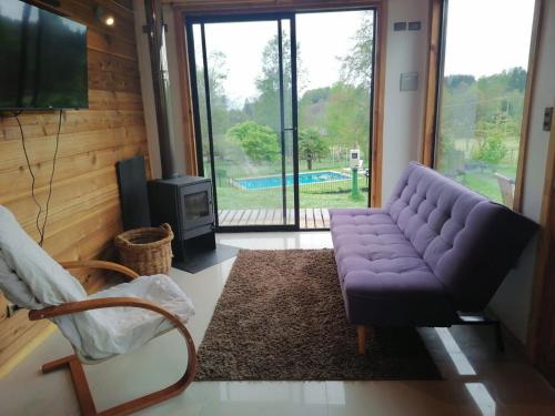 sala de estar con sofá púrpura y TV en Casa en Villarrica con vista al Volcán, en Molco