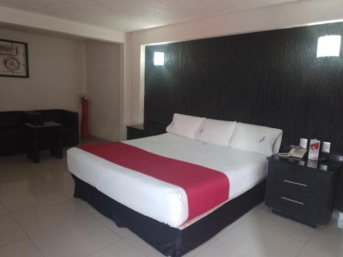 a bedroom with a large bed with a red and white blanket at HOTEL MORELOS in Guadalajara