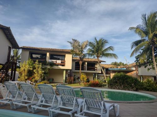 Un grupo de sillas junto a una piscina. en Pousada Aldeia Mar, en Ilhéus
