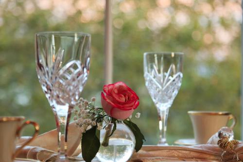 a table with three wine glasses and a rose in a vase at The Tower Cottage Bed and Breakfast in Point Pleasant Beach