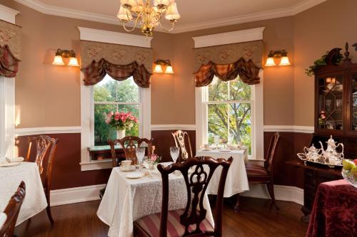 a dining room with two tables and two windows at The Tower Cottage Bed and Breakfast in Point Pleasant Beach
