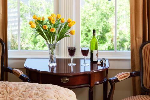 a table with two glasses of wine and a vase of flowers at The Tower Cottage Bed and Breakfast in Point Pleasant Beach