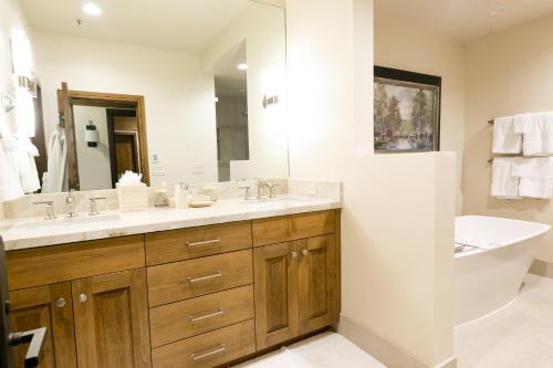 W łazience znajduje się umywalka, lustro i wanna. w obiekcie Deluxe King Room with Deck Hotel Room w mieście Park City