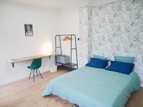 a bedroom with a blue bed and a desk at Le nid douillet de Sarreguemines in Sarreguemines