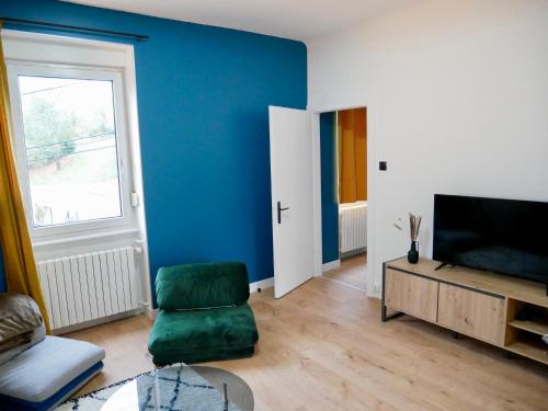 a living room with a green chair and a television at Le nid douillet de Sarreguemines in Sarreguemines