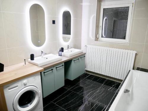 een badkamer met 2 wastafels en een wasmachine bij Le nid douillet de Sarreguemines in Sarreguemines