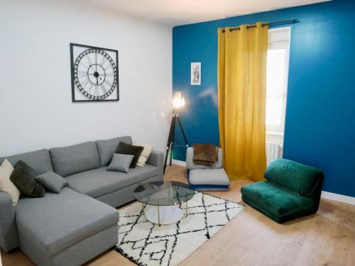 a living room with a couch and a chair and a clock at Le nid douillet de Sarreguemines in Sarreguemines