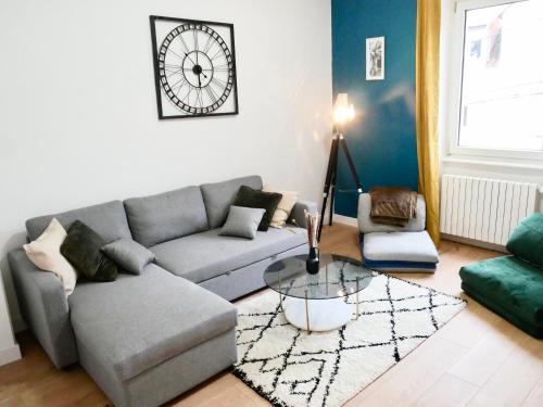 a living room with a couch and a clock on the wall at Le nid douillet de Sarreguemines in Sarreguemines