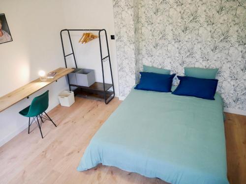a bedroom with a blue bed and a desk at Le nid douillet de Sarreguemines in Sarreguemines