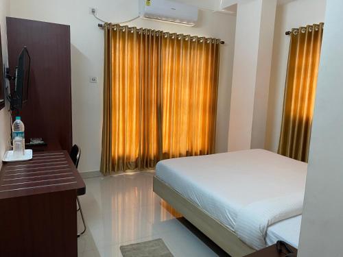 a bedroom with a bed and a desk and a window at Krishna Kunja " A Quiet & Peaceful Stay " in Kolkata