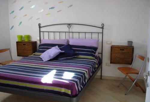 a bedroom with a bed with purple pillows and a chair at Domu Noa in Torre Dei Corsari