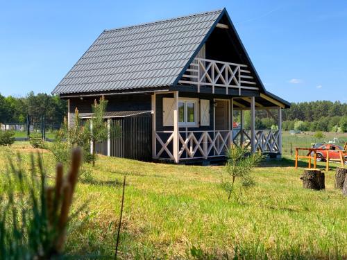a small house with a gambrel roof on a field at Prosportówek - Bronków - Domek nad Jeziorem w Otoczeniu Pięknych Lasów in Bronków